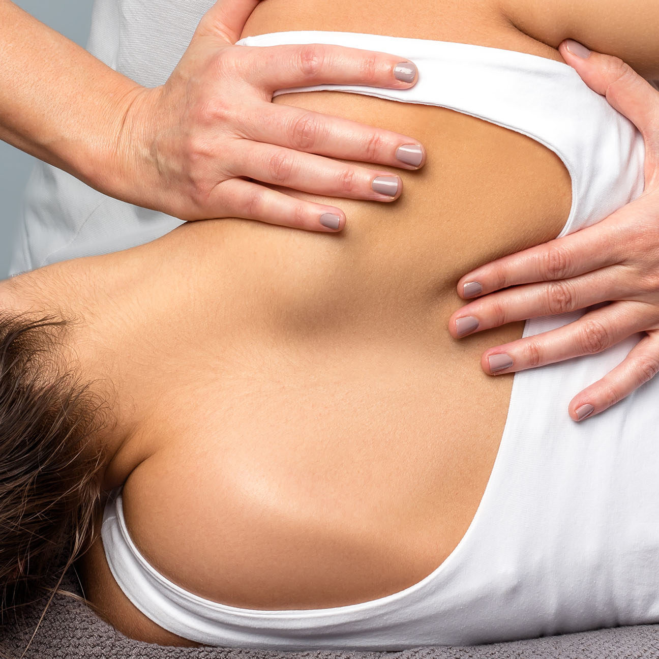 Detail of female therapist manipulating shoulder blade on patient.